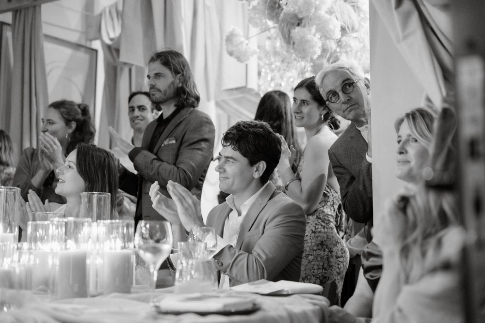 Wedding guests seated at tables with candlelight enjoy a reception dinner in black and white.
