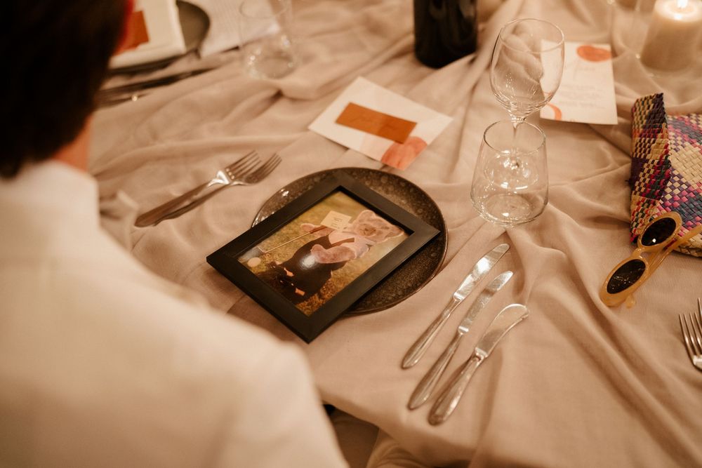 A wedding reception table setting with a framed photograph and place settings on a white tablecloth.