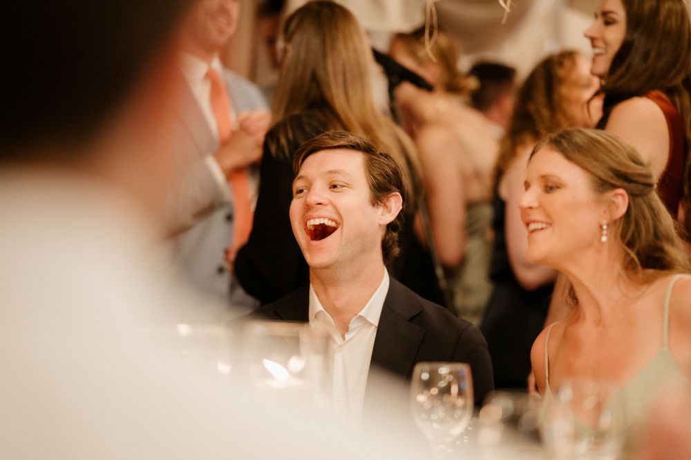 Candid reception moment capturing joyful laughter during wedding dinner.