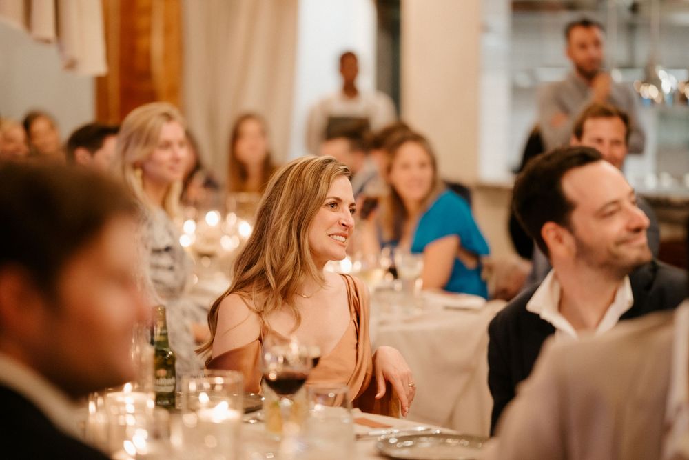 Guests enjoying an elegant candlelit wedding reception dinner at tables with white linens.