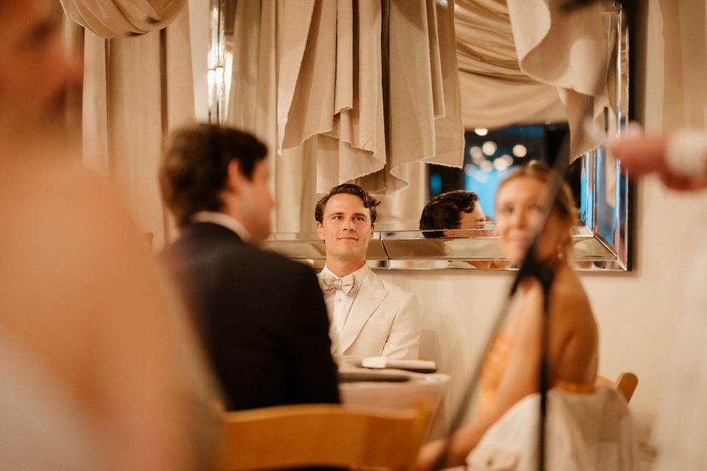 Wedding guests gather around an elegantly set table at an intimate reception dinner.