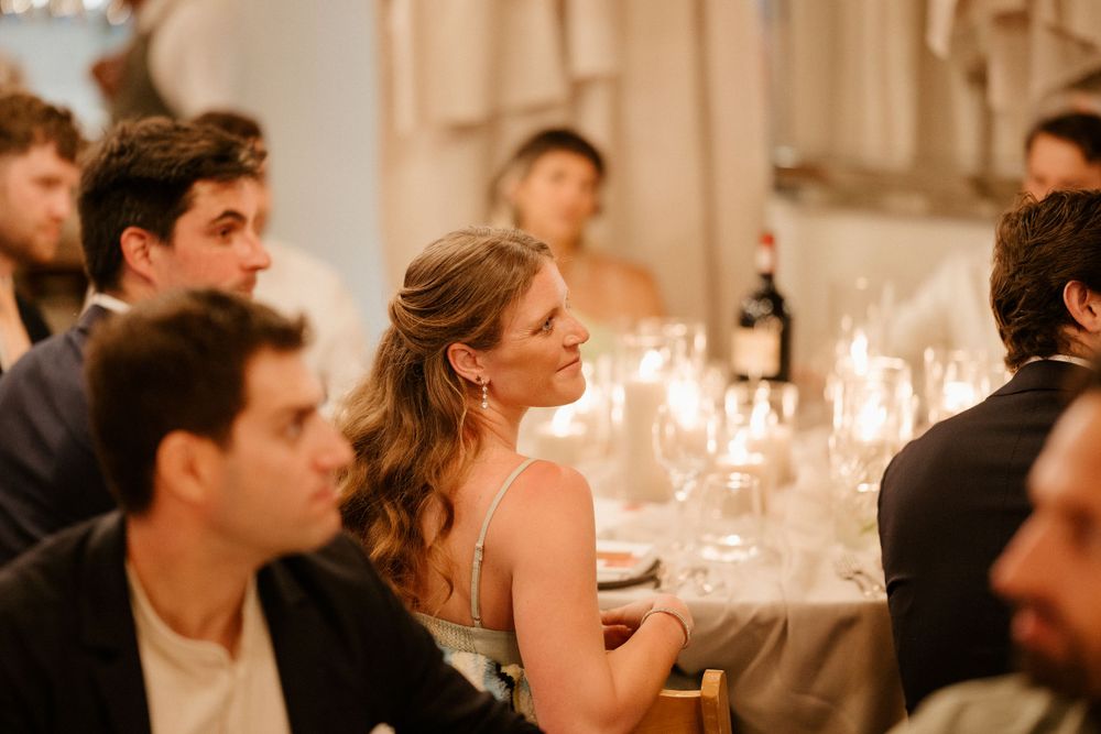 Wedding guests seated at elegant tables with candlelight creating a warm atmosphere.