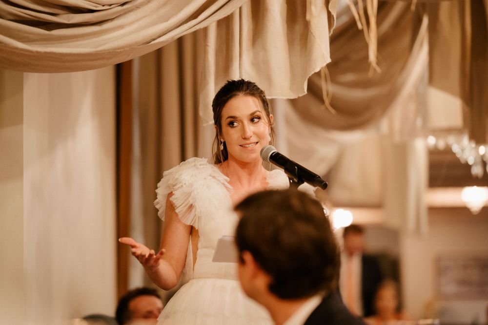 Wedding reception moment with white feather detail and elegant drapes in the background.