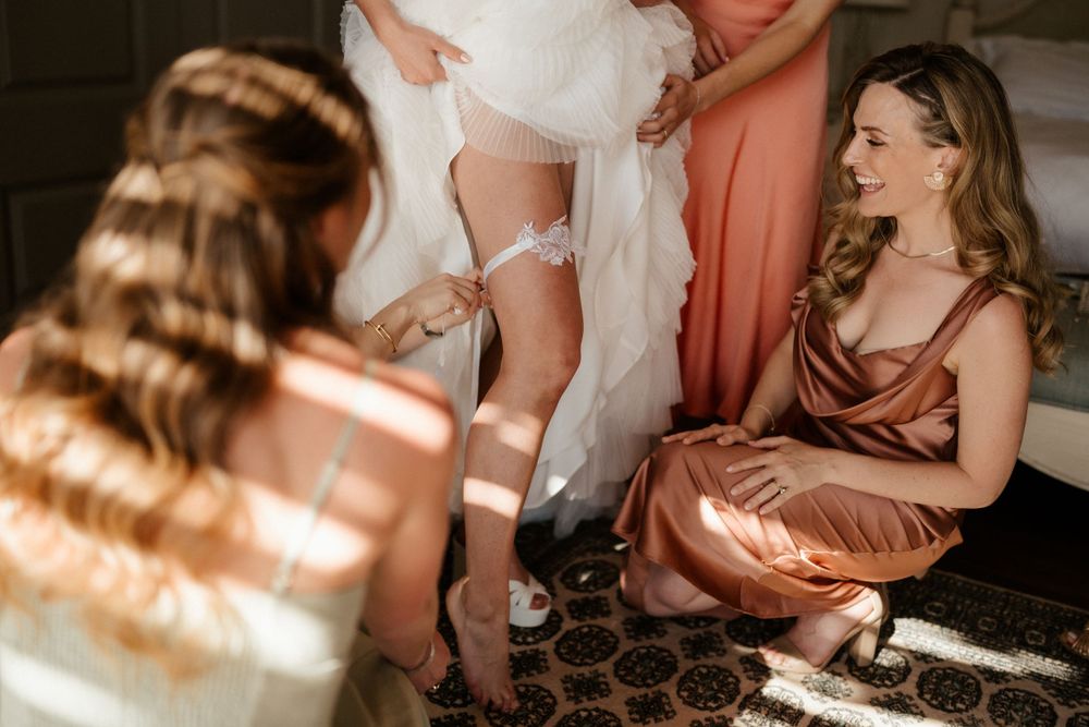 Wedding preparation moment showing dress details in warm interior lighting.