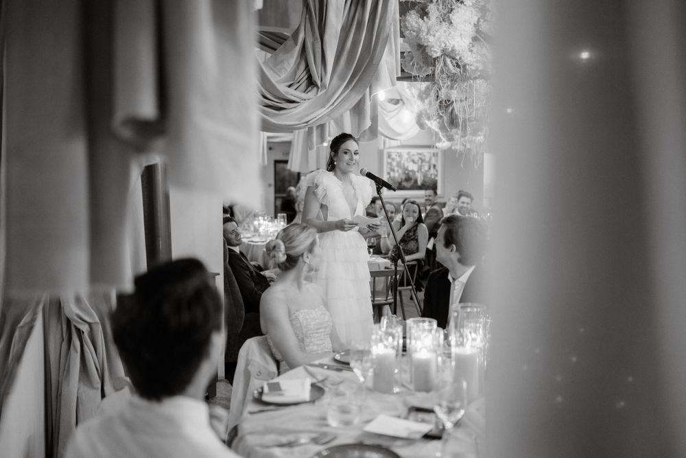 A black and white photograph of a wedding reception with candlelit tables and draped decor.