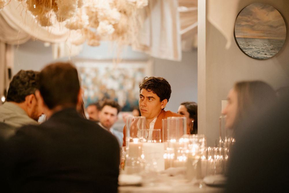 Guests enjoy an intimate candlelit dinner reception with elegant chandelier lighting and warm ambiance.