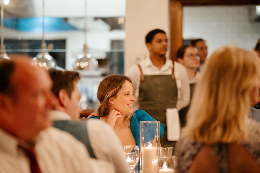 Candlelit wedding reception dinner with guests seated at tables in an intimate setting.