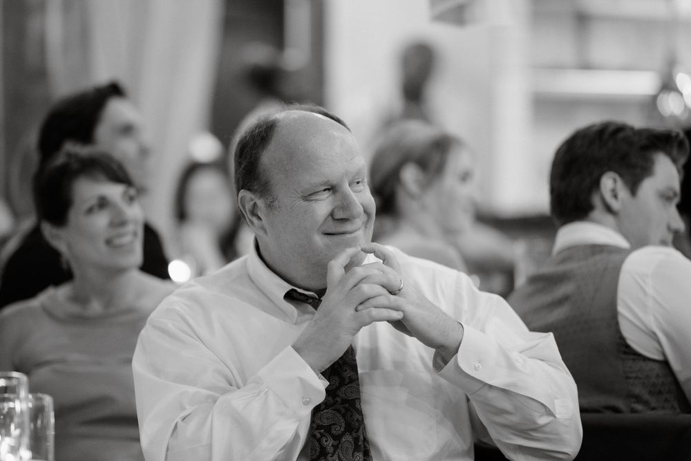 A candid black and white photo of a guest enjoying a moment at a formal dinner reception.