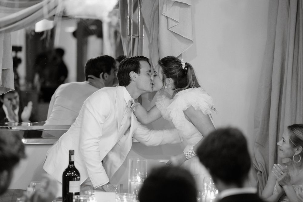 A black and white candid moment of romance during a wedding reception.