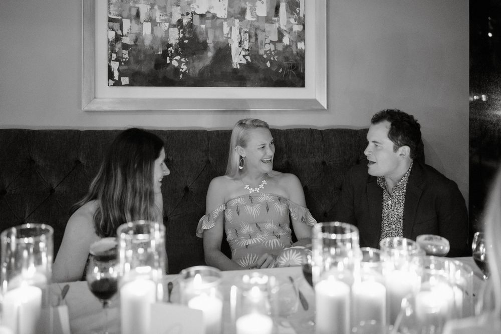 Guests engage in lively dinner conversation at an elegant candlelit reception table.