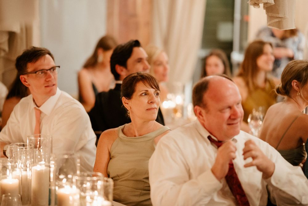 Wedding guests enjoy an intimate candlelit dinner reception with glowing ambiance and elegant table settings.