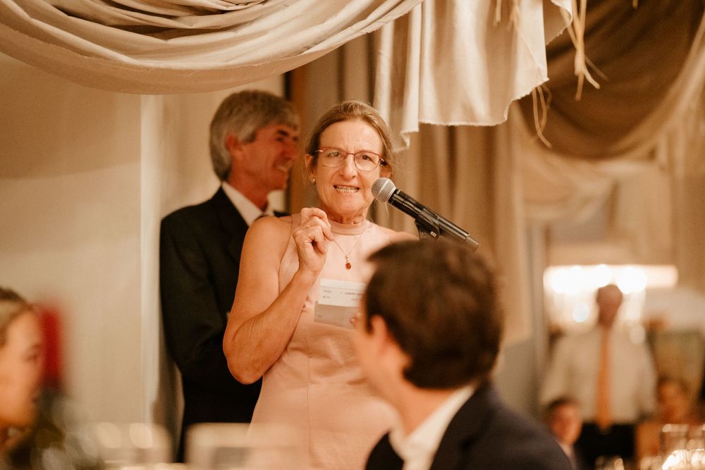 Warm-toned photo of emotional moment during wedding reception speeches.