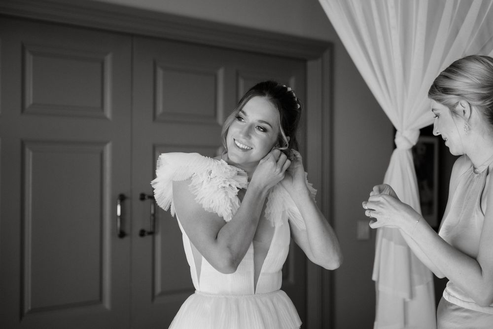 Black and white image showing wedding preparation moments in a sunlit room.