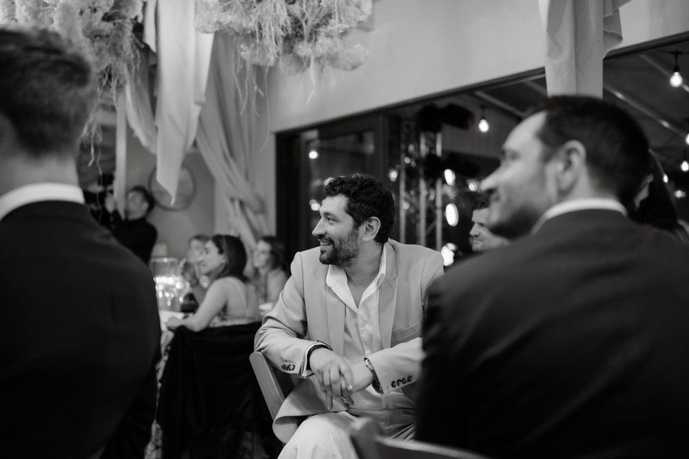 Black and white image of casual conversation during wedding reception.