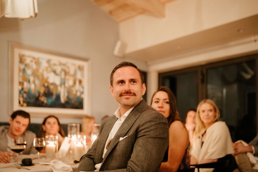 Guests enjoy an intimate dinner party with candlelight and warm ambiance at an elegant indoor gathering.