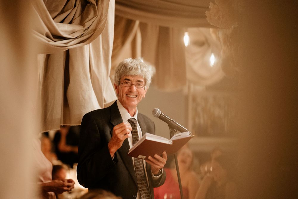 Wedding speaker delivering heartfelt speech at candlelit reception.