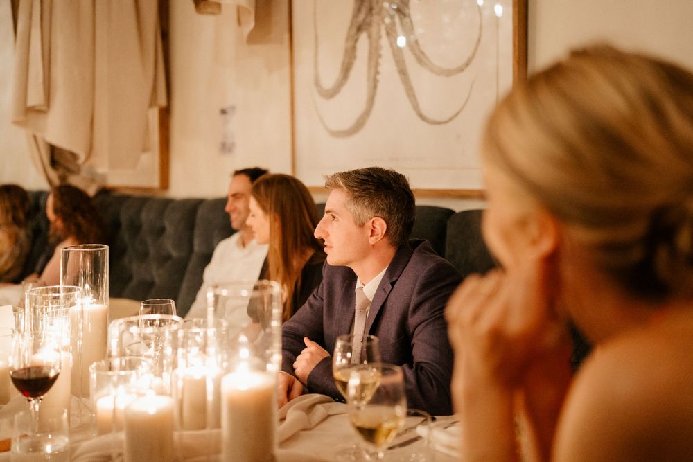 Intimate candlelit wedding dinner with guests engaged in conversation.