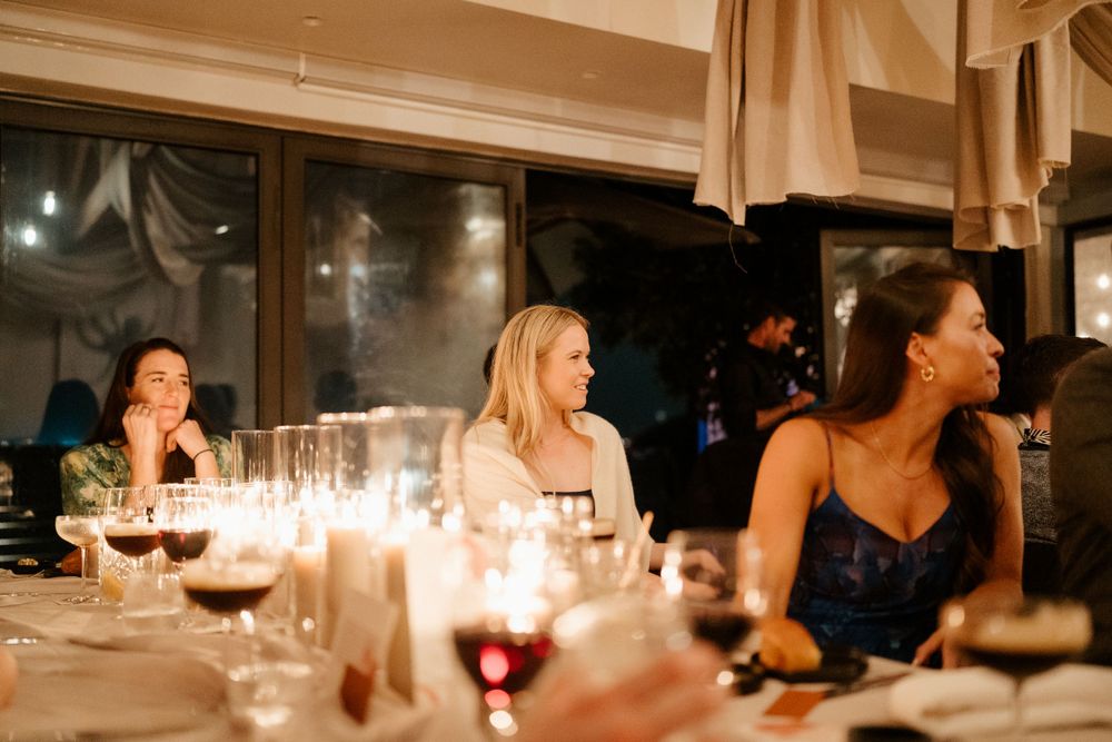 Dinner guests enjoying evening reception with candlelight and wine glasses.