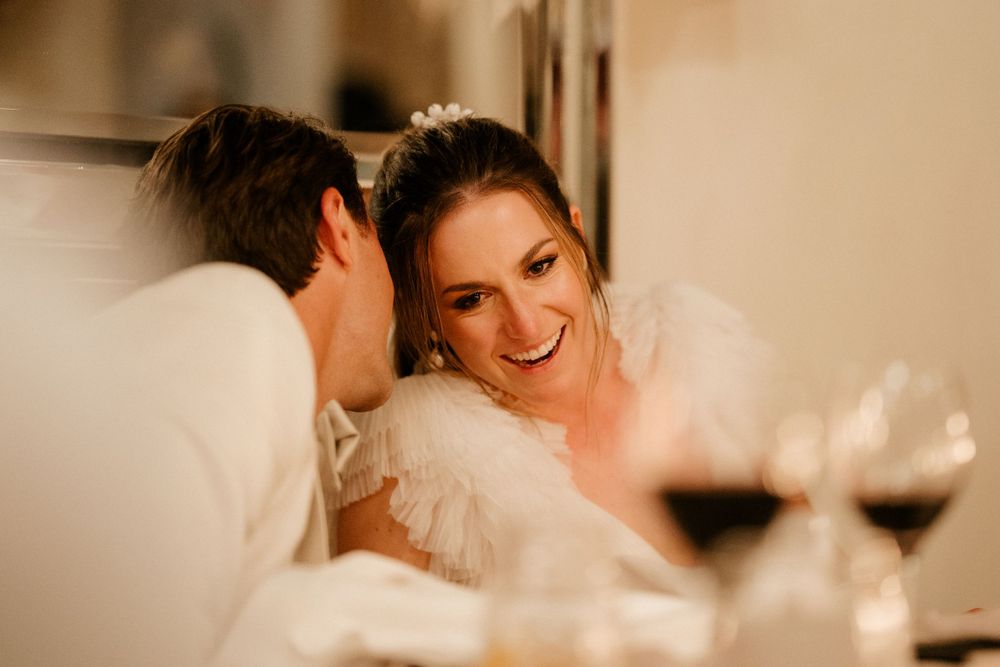 Candlelit reception moment with wine glasses and joyful laughter.