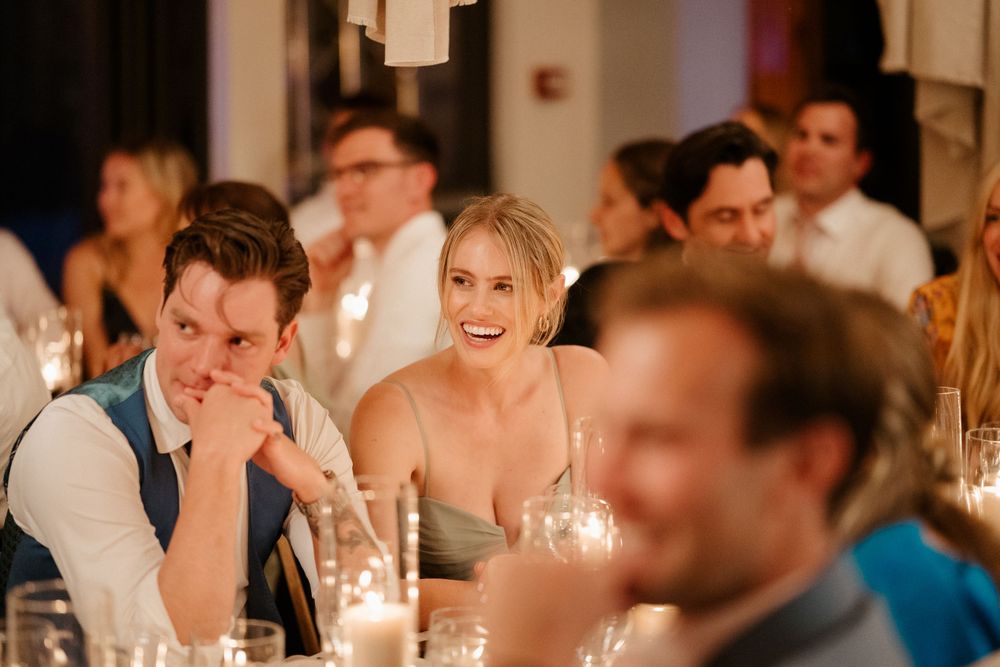 Wedding guests share joyful moments during an intimate candlelit dinner reception.