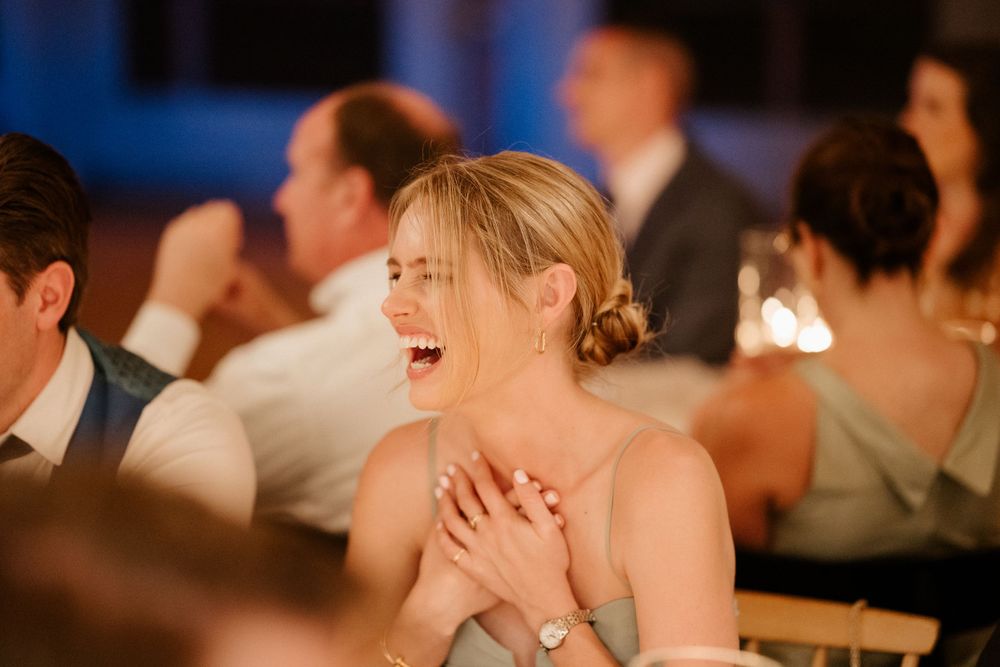 Candlelit reception guest reacts with joy and laughter during an emotional moment.