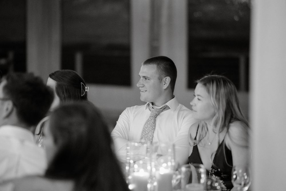 Wedding reception guests enjoy candlelit dinner conversation in an elegant indoor venue.