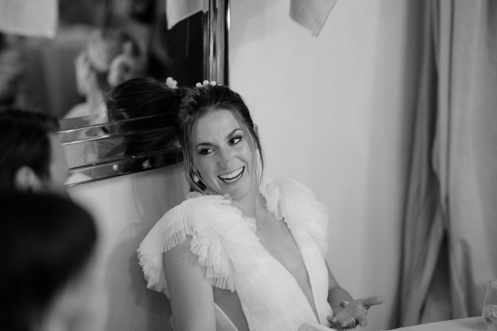 Black and white portrait of bride with feathered sleeve detail smiling.