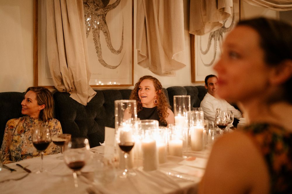 Candlelit dinner table with guests at elegant evening reception.