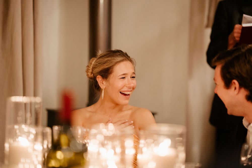 Joyful laughter shared across a candlelit table during an elegant wedding reception.