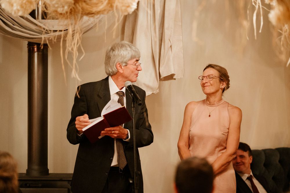 A speech being delivered during a wedding reception with elegant decor and soft lighting.
