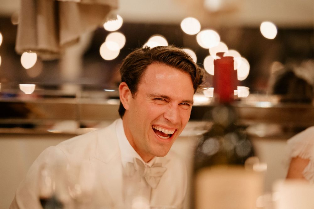 Candid reception moment captured in warm lighting showing joyful laughter.