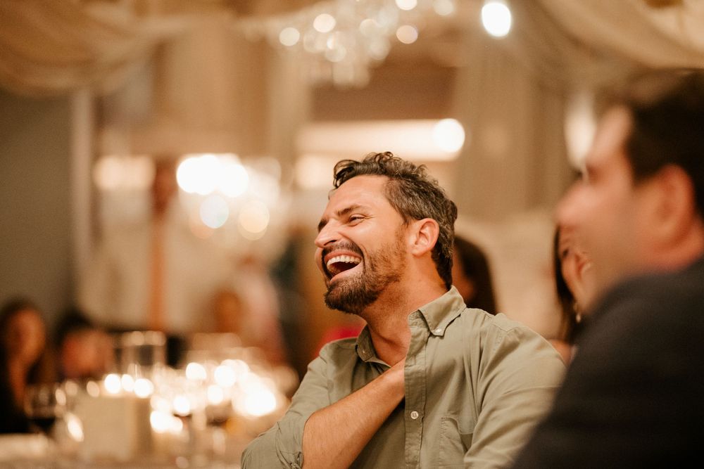 Guest laughing heartily during a joyful moment at a wedding reception.