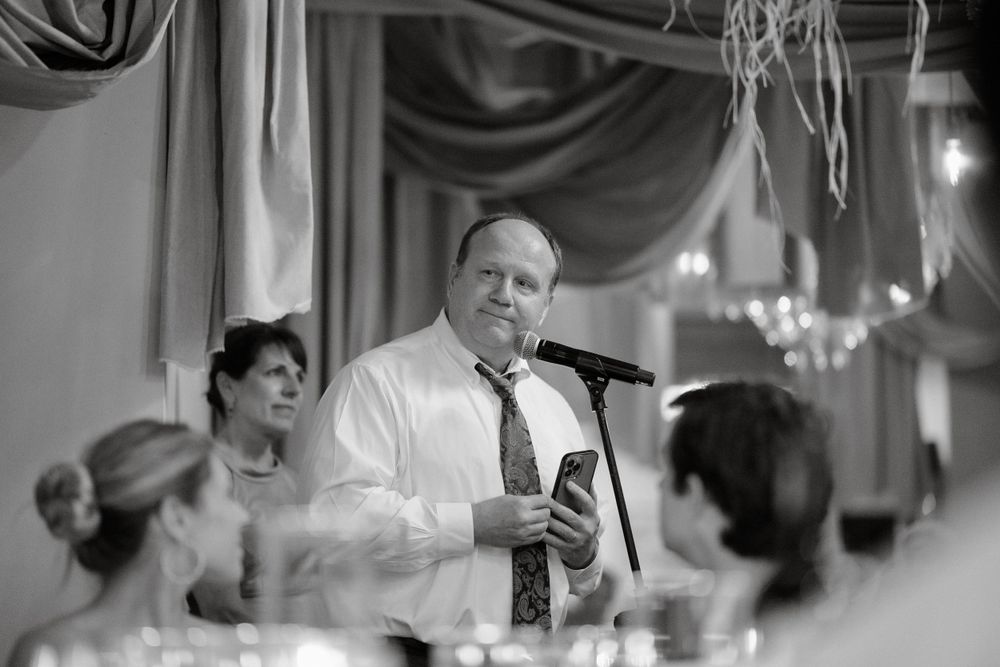 Black and white candid shot of a speech being given at an elegant wedding reception.