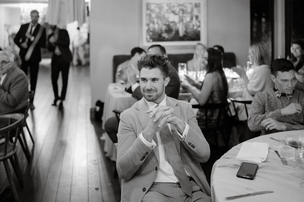 A guest at a wedding reception enjoying a laugh while seated at a round table.