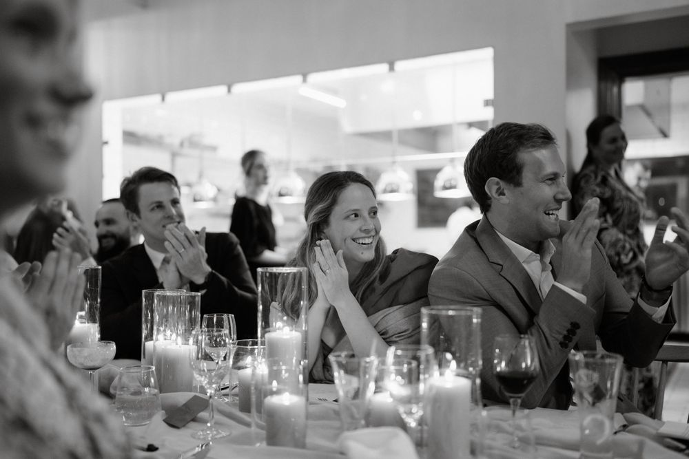 Black and white photograph captures emotional reactions during wedding reception speeches.