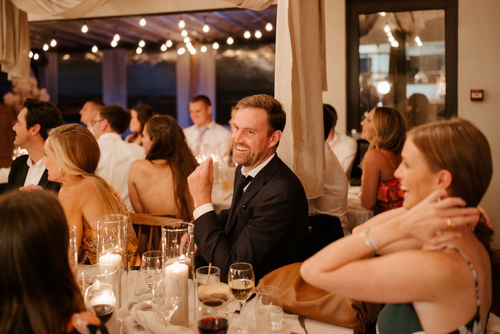 Wedding guests enjoying dinner and conversation at candlelit tables in an elegant venue.