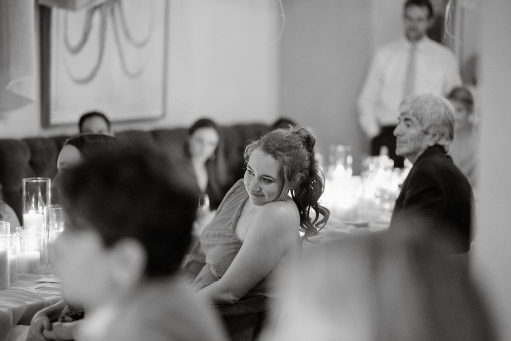 Black and white candid shot of wedding reception guests during dinner.