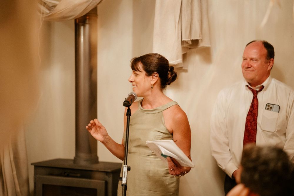 A speaker gives a toast at a wedding reception while holding a microphone.