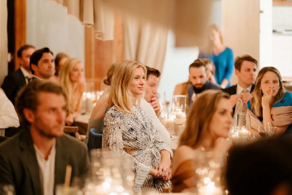 Wedding guests gathered at an elegant reception dinner with warm candlelight and ambient lighting.