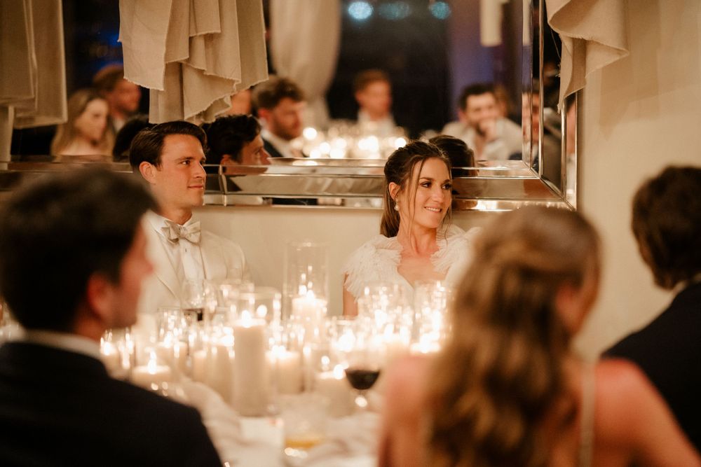 Intimate candlelit wedding reception dinner with guests seated at long tables.