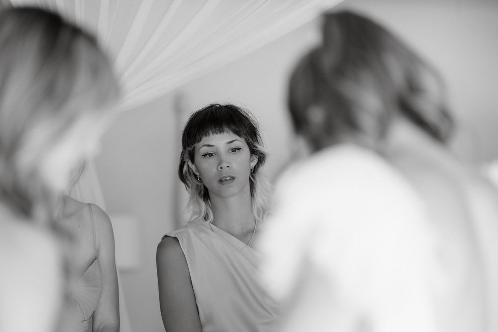 Black and white portrait of wedding preparations with soft fabric draping in background.