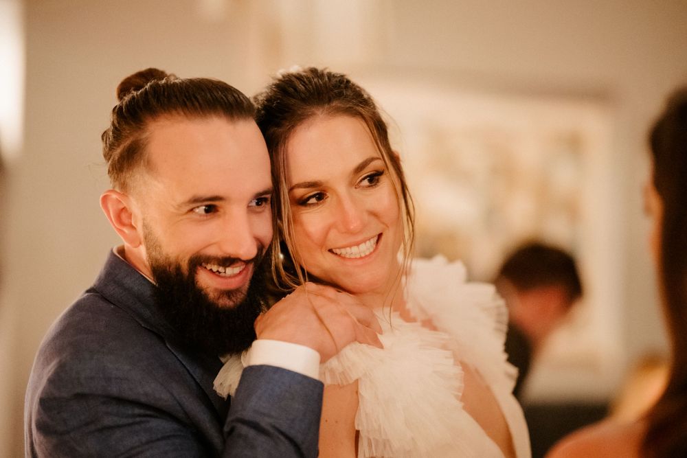 A romantic moment between newlyweds at their wedding reception in warm lighting.
