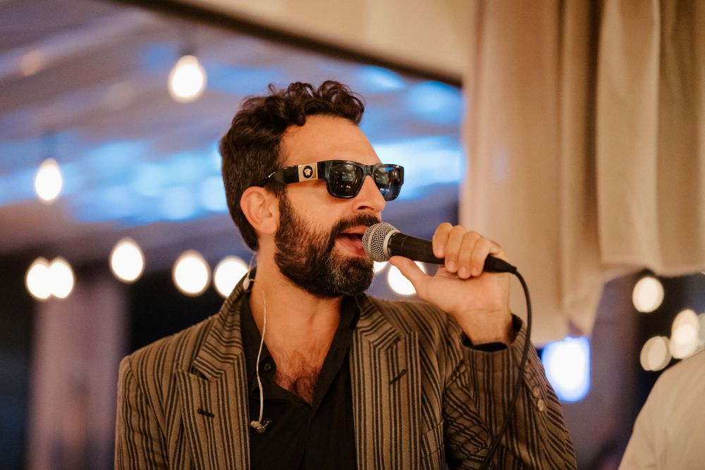 A smiling party guest in a striped blazer and sunglasses enjoying the festive atmosphere.