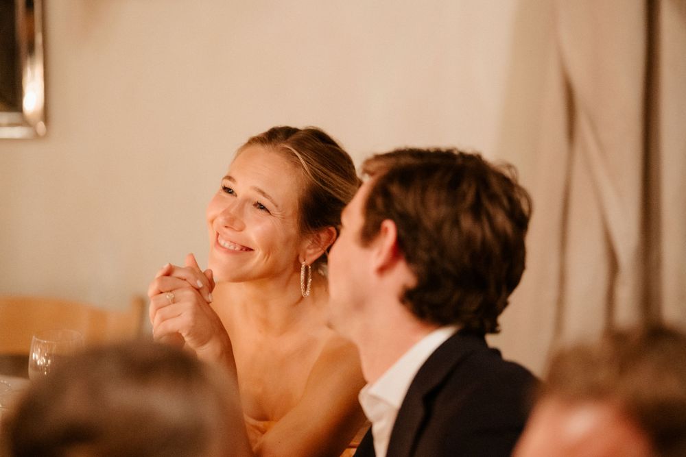 Candid reception moment captured during dinner speeches in warm lighting.