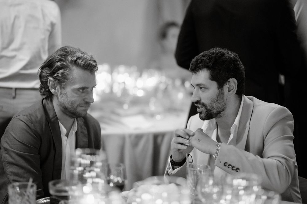 Two guests engaged in deep conversation at a dimly lit dinner table.