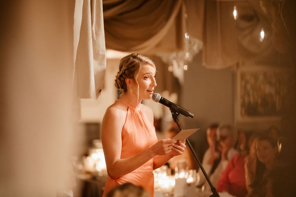 Warm-toned photo of wedding speech being delivered in decorated reception venue.