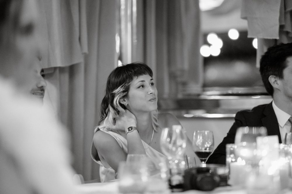 Elegant dinner party guest looks up thoughtfully during candlelit meal service.