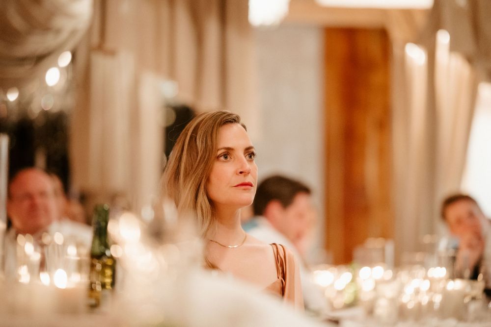 Elegant wedding reception guest illuminated by warm candlelight at dinner table.