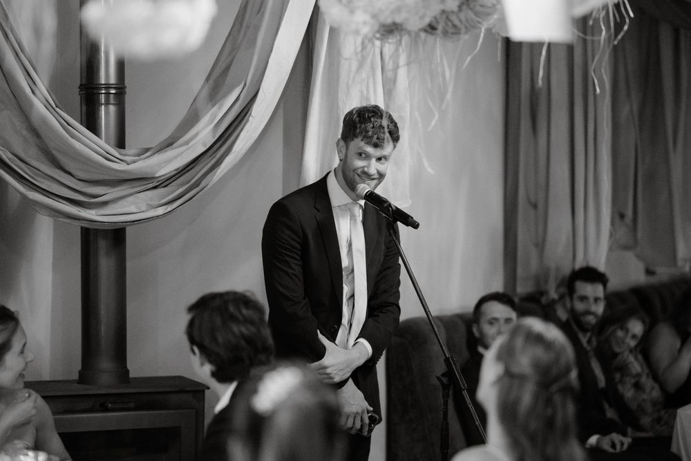 Black and white photo of wedding toast being given at formal reception.