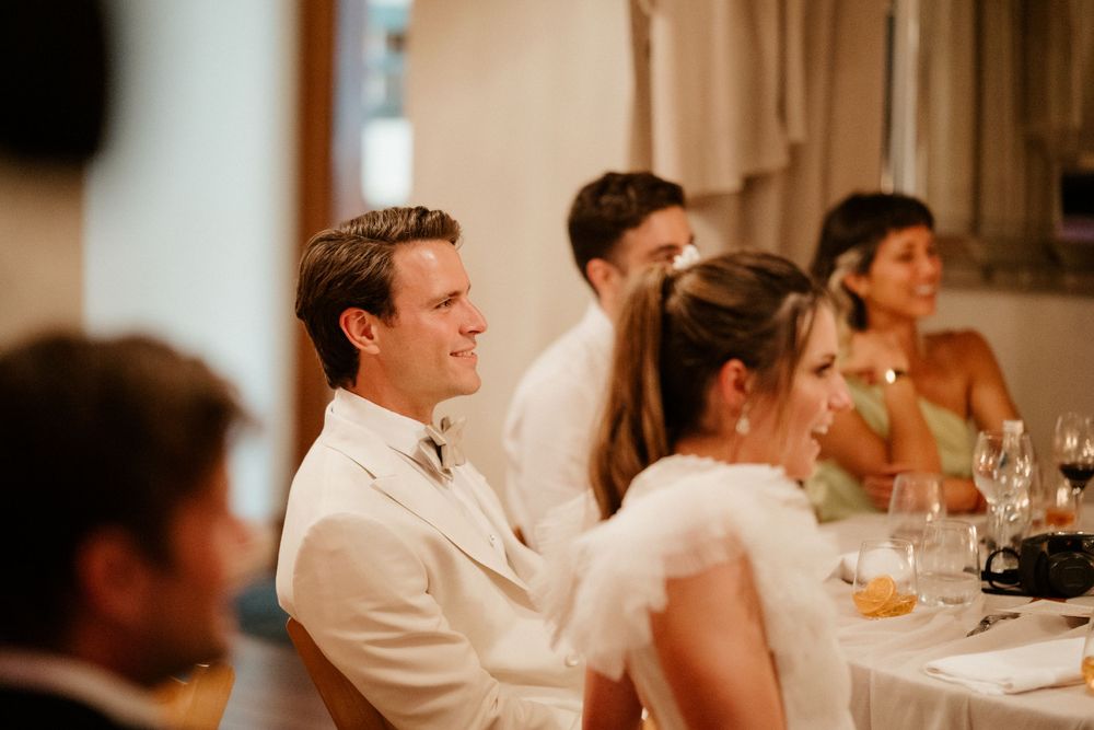 Guests seated at an elegant wedding reception dinner table with warm lighting.